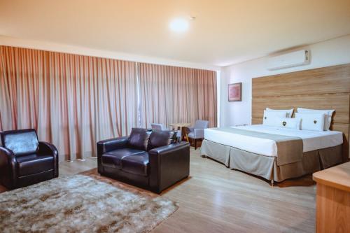 a hotel room with a bed and two chairs at Riellis Center Hotel in Botucatu