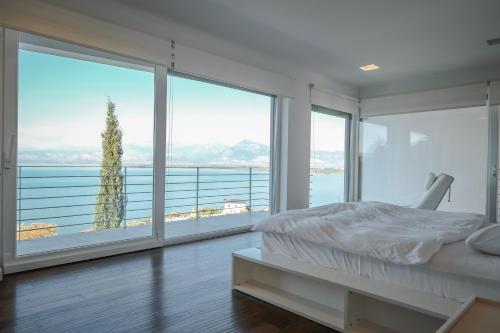 een slaapkamer met een bed en grote glazen ramen bij The White Villa in Široka