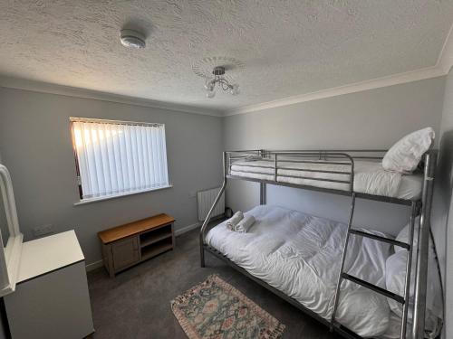a bedroom with two bunk beds and a desk at Cae Teg in Llanfairpwllgwyngyll