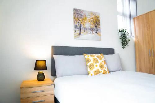 a bedroom with a bed and a night stand with a lamp at Bright 4BR Home, Perfect for Groups in Liverpool