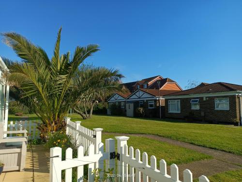 a white fence in front of a yard with houses at Cromarty Cottage Eastbourne in Pevensey