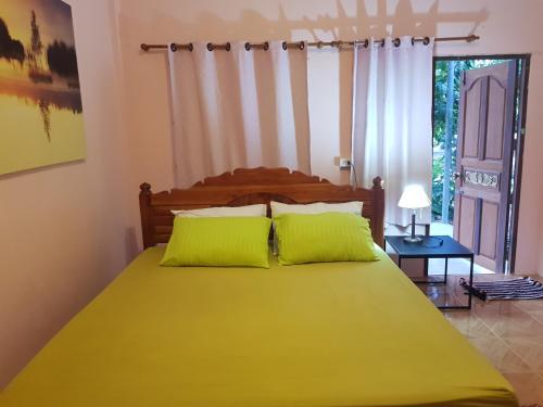 een slaapkamer met een groot geel bed met groene kussens bij โอคันทรี Ocountry in Khuang Nai