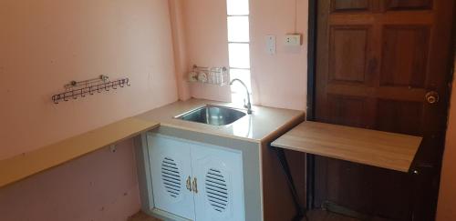 een kleine keuken met een wastafel en een deur bij โอคันทรี Ocountry in Khuang Nai