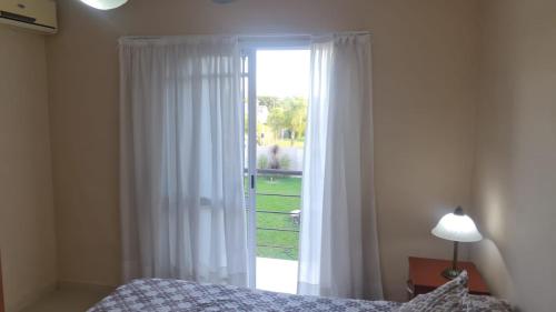 1 dormitorio con 1 cama y puerta de cristal con ventana en Departamentos Blanc en Colón