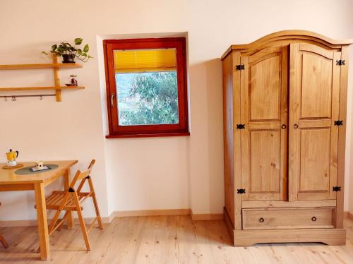 Cette chambre comprend une table, une fenêtre et une armoire en bois. dans l'établissement Residence Salvadori, à Rovereto