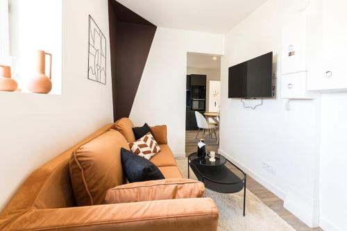 a living room with a couch and a tv at L'hermès, raffiné et élégant in Segré