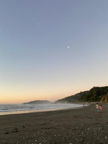 duas pessoas caminhando na praia ao pôr do sol em Cabañas Rumi Loft em Valdivia