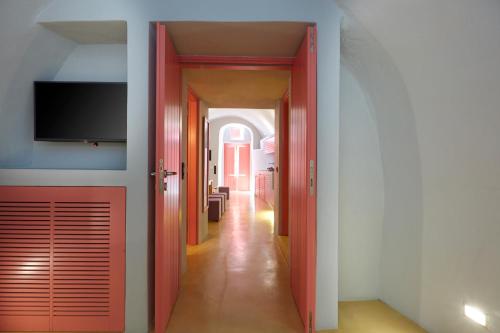 a hallway with red doors and a television on a wall at EDGE ON VOLCANO SUITES in Fira