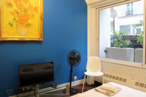 un salon avec un mur bleu et une télévision dans l'établissement Colored Appt To Beaugrenelle, à Paris