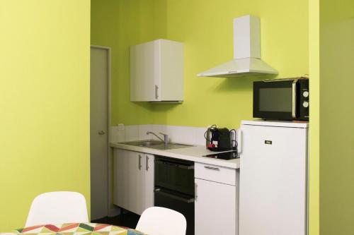 La cuisine est équipée d'un réfrigérateur blanc et d'un four micro-ondes. dans l'établissement Colored Appt To Beaugrenelle, à Paris