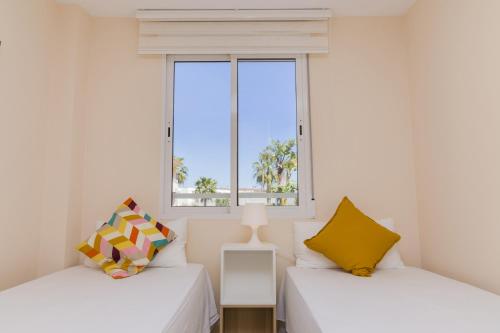 deux lits dans une chambre avec une fenêtre dans l'établissement Veranda Golden Beach II Apartment Javea Arenal, à Jávea