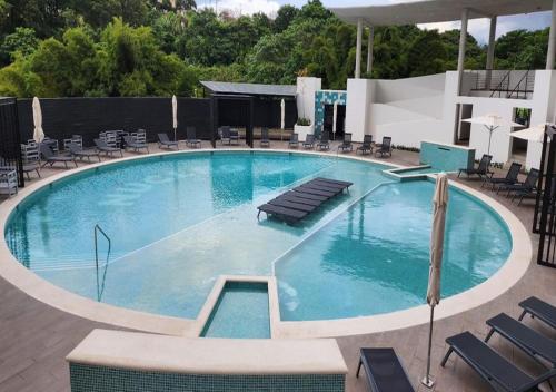 een groot blauw zwembad met stoelen en tafels bij Chic & Stylish: Prime Apartment in La Sabana, Your Ideal Urban Oasis Awaits in Uruca