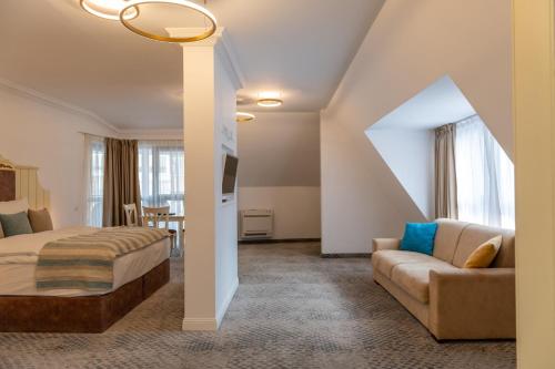 um quarto de hotel com uma cama e um sofá em ATLAS HOUSE Luxury Suites em Plovdiv