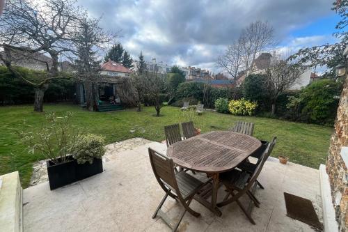 een houten tafel en stoelen op een patio bij Villa and garden near Paris for the Olympic games in Garches