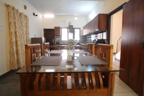 een eetkamer met een lange tafel en stoelen bij Joann Serviced Apartment in Thiruvalla