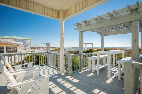 a porch with white chairs and tables on a deck at Fairwinds by Oak Island Accommodations in Caswell Beach
