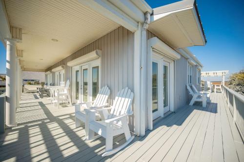 a porch with white rocking chairs on a house at Fairwinds by Oak Island Accommodations in Caswell Beach