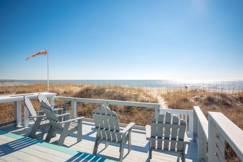 a deck with chairs and a view of the beach at Fairwinds by Oak Island Accommodations in Caswell Beach
