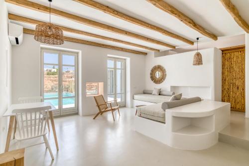 a white living room with a bed and a table at Lil Paros Luxury suites in Dhragoulás