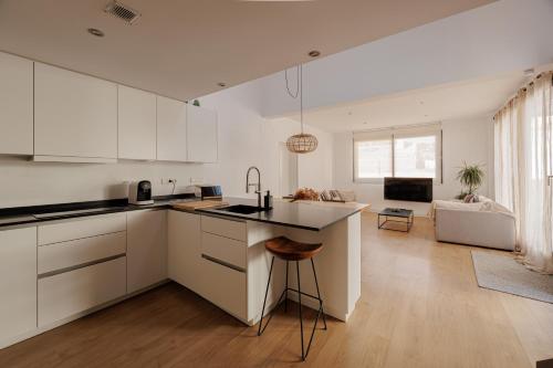 uma cozinha com armários brancos e uma ilha de cozinha em Atico Duplex Playa Area Barcelona con SPA exterior em Montgat