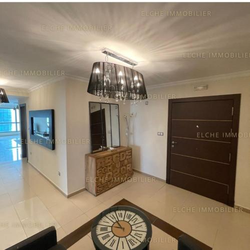 ein Wohnzimmer mit einem Kronleuchter und einer Uhr in der Unterkunft Appartement mobilart in Oran
