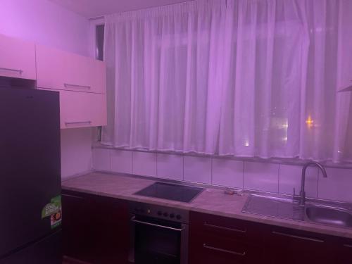 cocina con fregadero y ventana con iluminación rosa en Mezes fushe Kashar, en Tirana