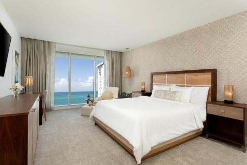 ein Schlafzimmer mit einem großen Bett und einem großen Fenster in der Unterkunft Casa Costera, Isla Verde Beach, Apartments by Marriott Bonvoy in San Juan