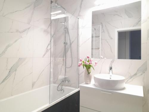 a white bathroom with a sink and a shower at Vista Residence Wola in Warsaw