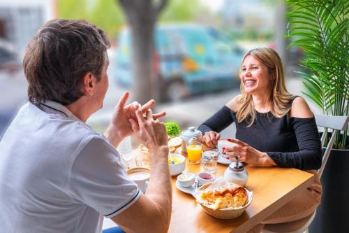 un hombre y una mujer sentados en una mesa comiendo comida en Modern Apartments in Palermo en Buenos Aires