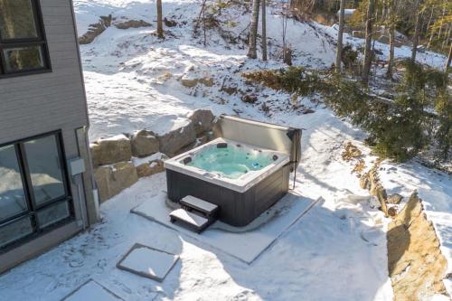 una bañera de hidromasaje en la nieve junto a una casa en Perché Private Hot Tub Pool Table Peaceful, en Brownsburg