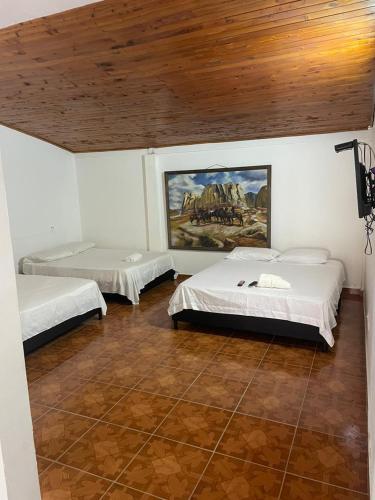 um quarto com duas camas e um quadro na parede em HOTEL CAMPESTRE REFUGIO TEXANO em Puerto Triunfo