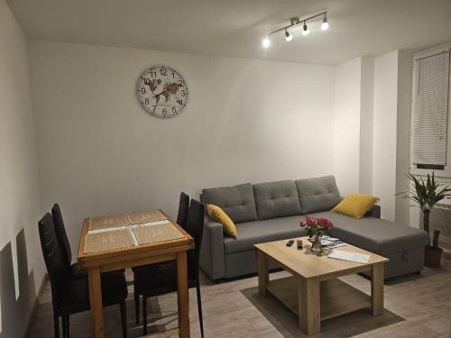 a living room with a couch and a table and a clock at Joli appartement en face de lac in Nantua
