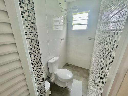 聖塞巴斯蒂安的住宿－Chalé Bromélia，白色的浴室设有卫生间和窗户。