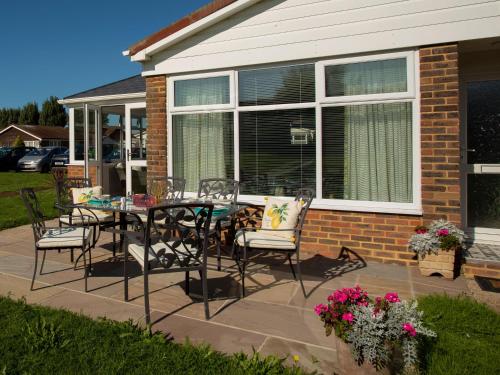 a patio with a table and chairs in front of a house at Harbour cottage sleeps 4 nr Marina Eastbourne in Pevensey