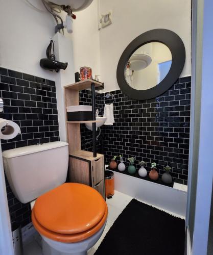 La salle de bains est pourvue de toilettes orange et d'un miroir. dans l'établissement Le chantenay, à Nantes