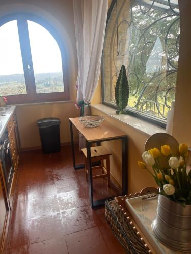 a kitchen with two windows and a table with flowers at mikipongTWO in Montepulciano
