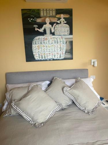 a bed with pillows and a painting on the wall at mikipongTWO in Montepulciano