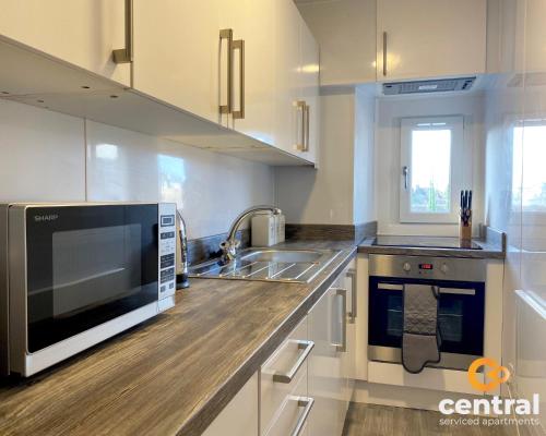 a kitchen with a sink and a microwave at Lawson by CENTRAL SERVICED APARTMENTS - Cosy 1 Bedroom - Modern - Close to Transport Links - Quiet Neighbourhood - Fast WiFi - Fully Equipped - Smart TVs in All Rooms - Monthly Stays Welcome - FREE Street Parking - Ideal Relocation to Dundee Accommodation in Dundee