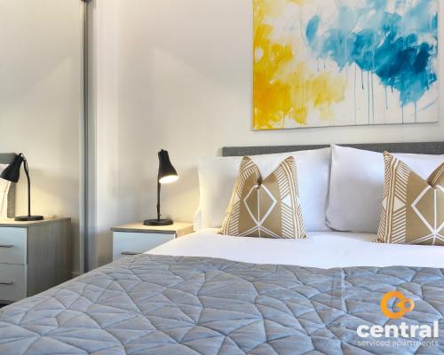 a bedroom with a bed with pillows and a painting at 2 Bedroom Apartment by Central Serviced Apartments - Monthly Bookings Welcome - FREE Street Parking - WiFi - Smart TV - Ground Level - Family Neighbourhood - Sleeps 4 - 1 Double Bed - 2 Single Beds - Heating 24-7 - Trade Stays - Weekly & Monthly Offers in Dundee