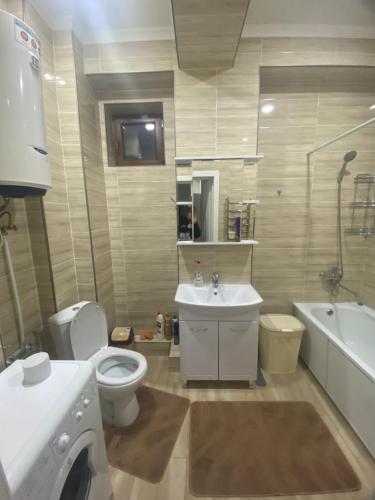 een badkamer met een toilet, een wastafel en een wasmachine bij Kojomkul in Bisjkek