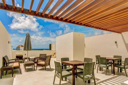 a patio with tables and chairs and an umbrella at Akumal Heaven Beach Access 7 Rooftop Pools W Caribbean Sea Views + Beach Club in Akumal
