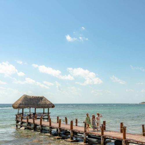 a group of people walking on a dock in the ocean at Akumal Heaven Beach Access 7 Rooftop Pools W Caribbean Sea Views + Beach Club in Akumal