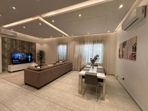 Smart luxury apartment 3bedrooms في الرياض: غرفة معيشة كبيرة مع أريكة وتلفزيون