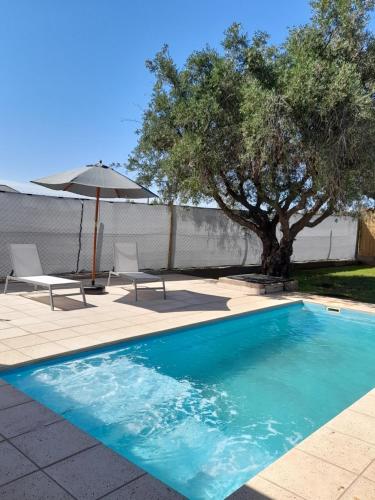 a swimming pool with two chairs and an umbrella at Olivos Luján in Ciudad Lujan de Cuyo