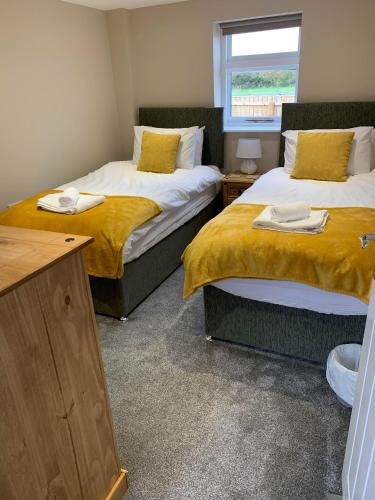 a room with two beds with yellow sheets and a window at The Dairy, quiet countryside location near York in Wilberfoss