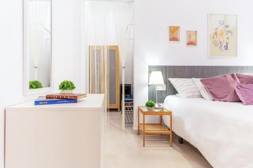 a white bedroom with a bed and a table at AlohaMundi San Esteban III in Seville