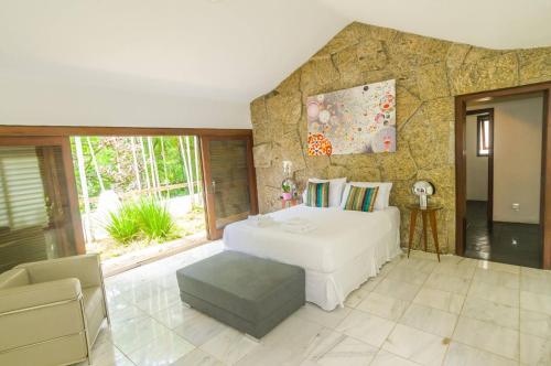 a bedroom with a white bed and a stone wall at Les Jardins de Rio Boutique Hotel in Rio de Janeiro