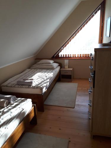 PécselyにあるKikapcsol-lakのベッド2台と窓が備わる屋根裏部屋です。