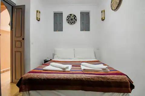 a bedroom with a bed with towels and a clock on the wall at Riad Azawan in Marrakech