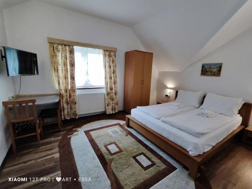 a bedroom with a bed and a desk and a television at Pensiunea Buon Gusto Sibiu-motorcyle friendly,city center in Sibiu